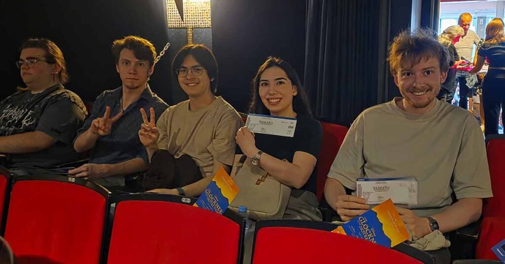 A group of students sitting in a theater holding tickets to the Yamato Drummers of Japan performance.